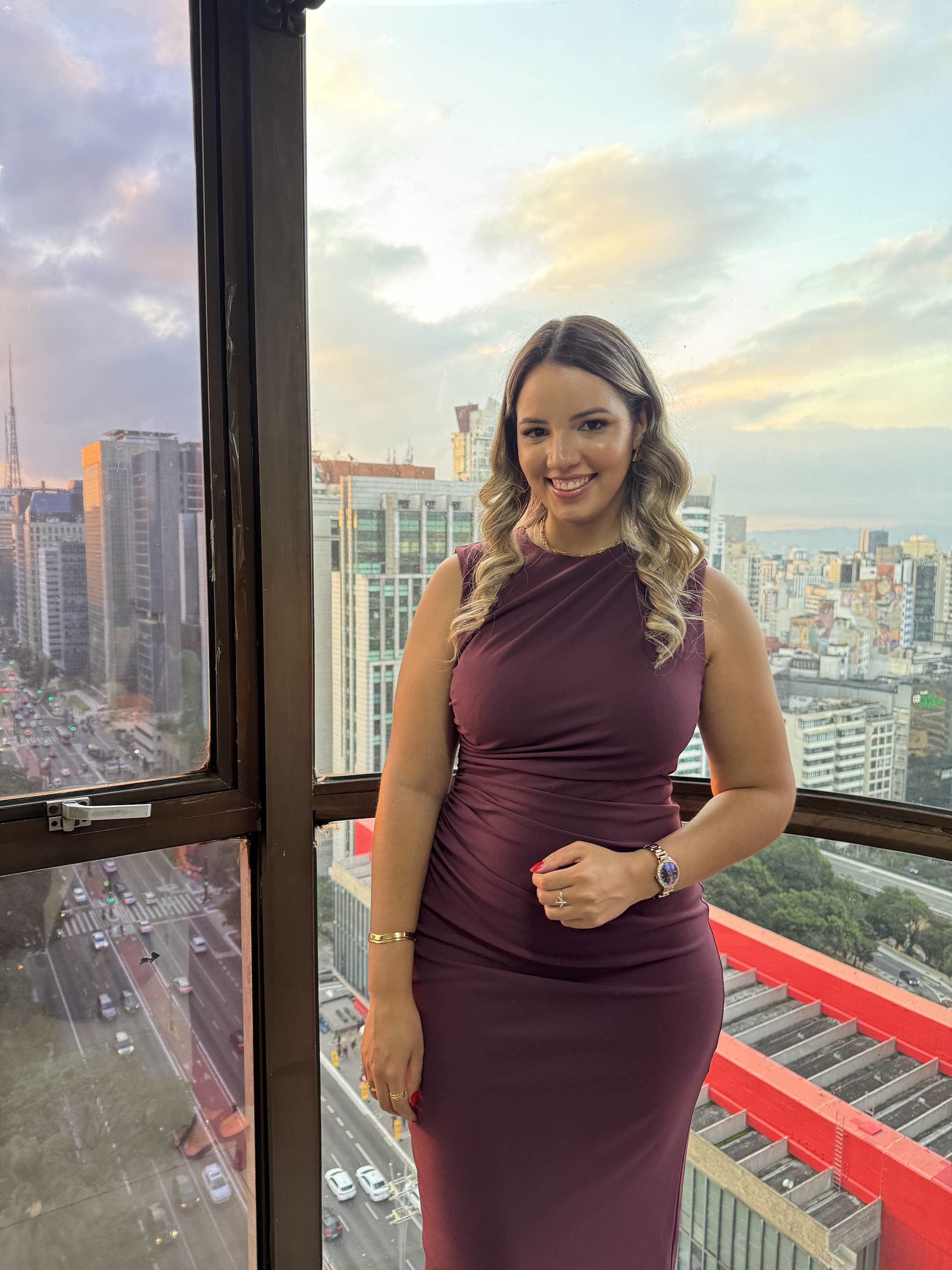 Stefany sorrindo no fim de tarde, com a Avenida Paulista ao fundo, na edição de 2025
